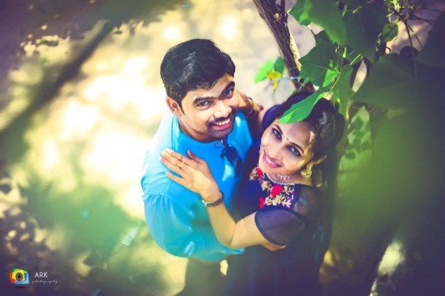 Couple embracing under a tree, framed by green leaves