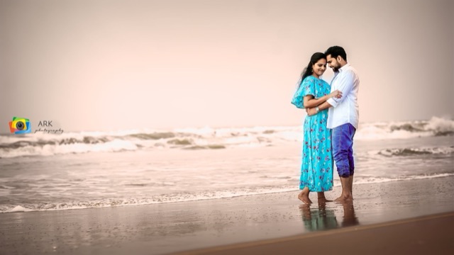 Couple standing together on the beach at the water's edge