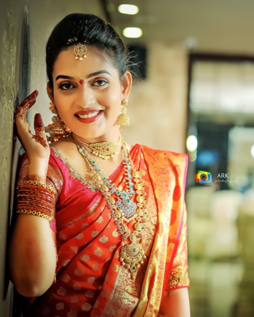 Smiling bride in a red silk saree with traditional jewellery