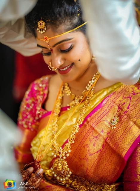 Close portrait of a bride in a gold silk saree and temple jewellery