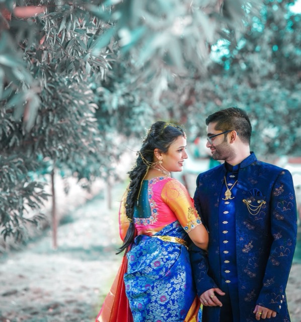 Couple in festive outfits posing among trees