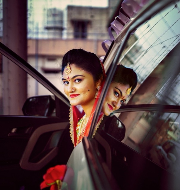 Bride smiling from the open door of the wedding car