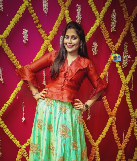 Young woman posing in front of red and marigold event decor