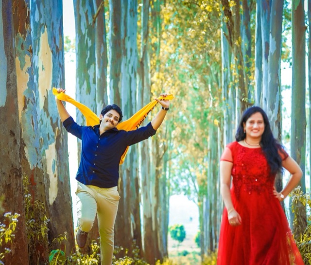 Couple posing playfully among tall eucalyptus trees