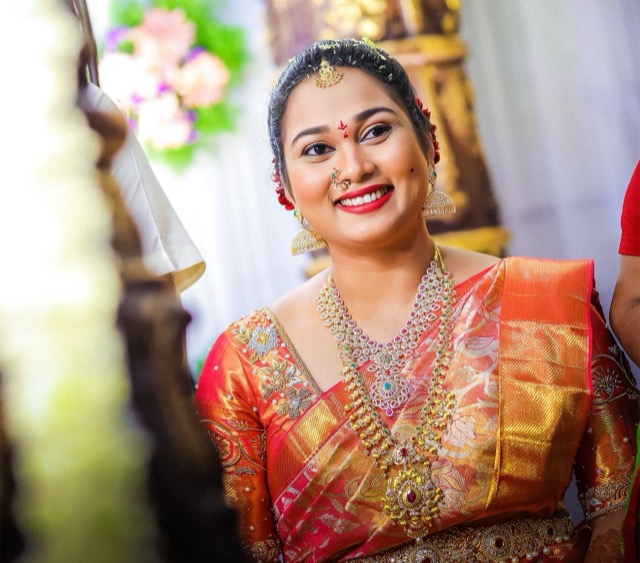Joyful bride in a red silk saree with gold jewellery