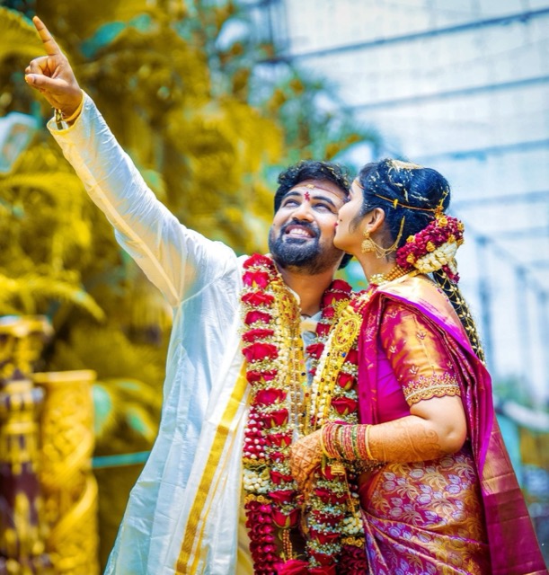 Groom and bride wearing wedding garlands, sharing a joyful moment
